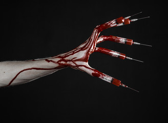 Obraz na płótnie Canvas Bloody hand with syringe on the fingers, toes syringes in studio
