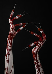 Bloody hand with syringe on the fingers, toes syringes in studio