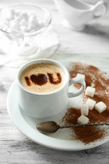 Cup of latte coffee art on wooden table, on light background
