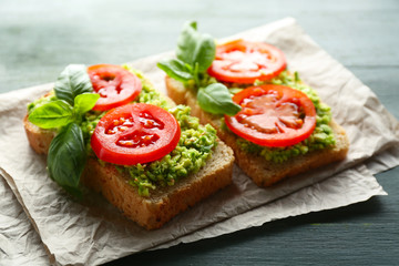Vegan sandwich with avocado and vegetables on wooden background