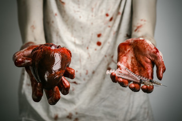 bloody hands addict holding syringe and bloody human heart