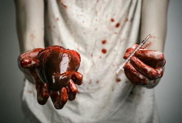 bloody hands addict holding syringe and bloody human heart