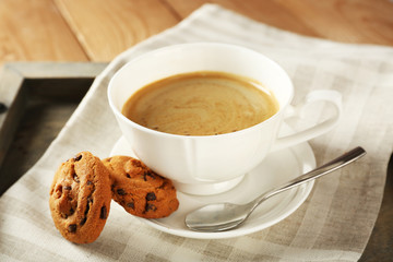 Cup of coffee with cookie on table, closeup