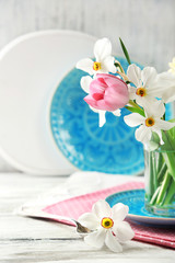 Spring bouquet in glass mug on color wooden background