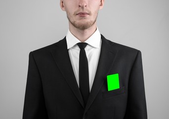 businessman in a black suit and black tie holding a green card