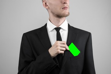 businessman in a black suit and black tie holding a green card