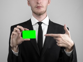 businessman in a black suit and black tie holding a green card