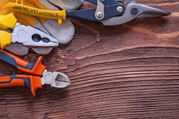 Nippers pliers wire-cutter and construction glove on wood board 