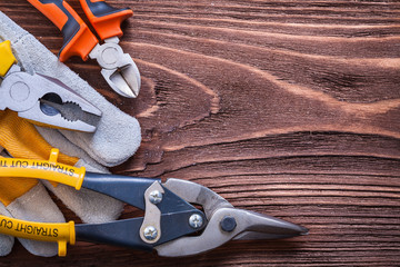 Nippers pliers wire-cutter and protective glove on wood board co