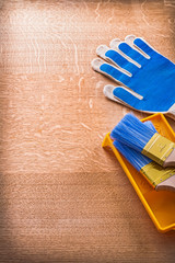 Protective gloves with paint tray and brushes on wood board cons