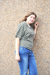 Female tomboy standing against a wall out side.