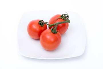 grappolo di tre pomodori rossi su un piatto