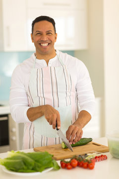 man chopping cucumber in kitchen