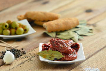 Antipasti - Eingelegte Tomaten auf Teller und Holztisch