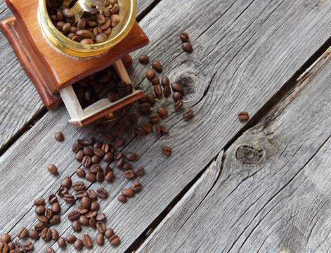 Coffee grains and manual mill on a wooden table
