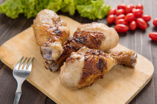 Grilled chicken legs BBQ on a wooden board.