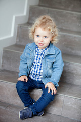 Blond baby sitting on the stairs at home