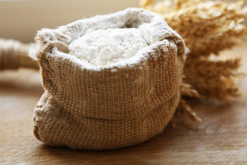 Flour in burlap bag on wooden background