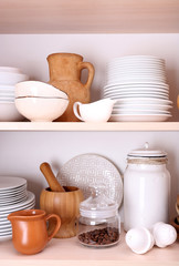 Kitchen utensils and tableware on wooden shelves
