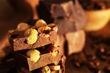 Stack of chocolate with nuts on wooden table, closeup