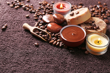 Composition of soap, chocolate in bowl and coffee beans on brown towel background