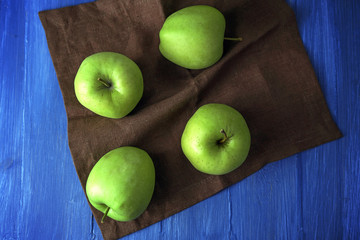 Green apples on wooden table with napkin, top view