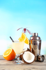 Glass of summer cocktail on wooden table on bright blurred background