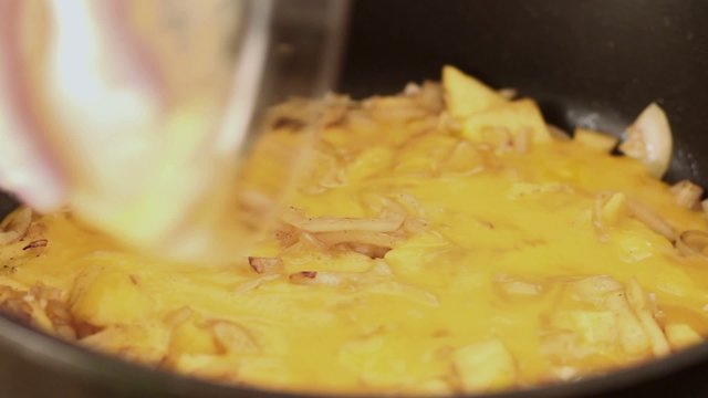 Omelet making, pouring eggs into hot pan closeup
