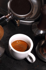 Porcelain white cup of coffee and portafilter of an espresso machine
