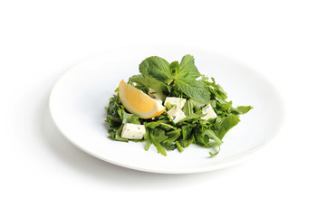 Green salad with cheese, lettuce, mint, rucola and lemon isolated on white