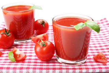 Glasses of fresh tomato juice on checkered napkin, isolated on white
