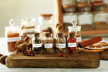 Fototapeta na wymiar Assortment of spices in glass bottles on cutting board, on wooden background