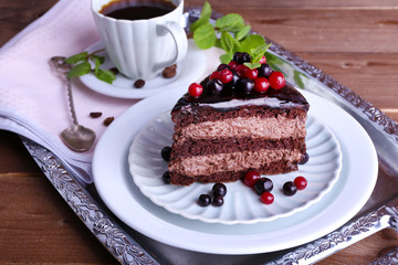 Delicious chocolate cake with berries and cup of coffee on table close up