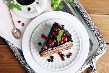 Delicious chocolate cake with berries and cup of coffee on table close up