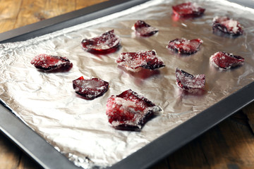 Candied sugared roses petals on foil, on wooden background