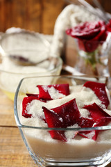 Making candied rose flower petals with egg whites and sugar, on wooden background