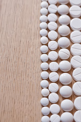 Different white pills on the wooden background