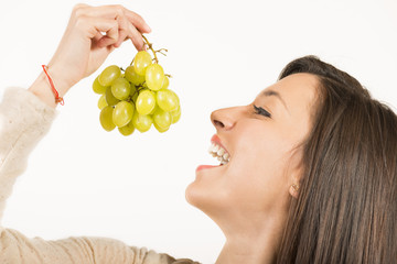 Close up portrait of young woman eating white grapes.