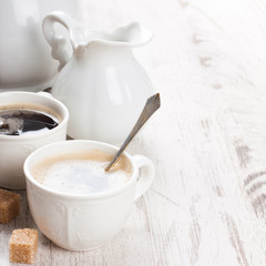 Cup of coffee with sugar cubs and milk jug
