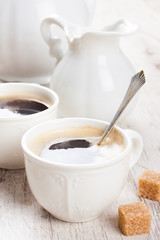 Cup of coffee with sugar cubs and milk jug
