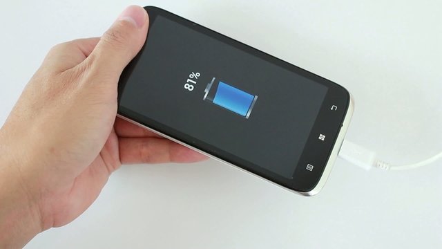 male hand plugging in the plug of her smartphone in a socket