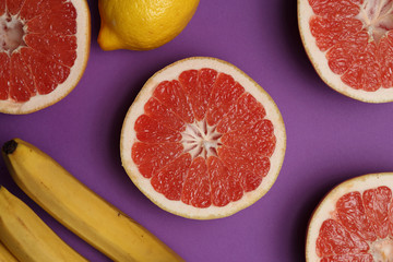 Lemon, grapefruits and bananas on bright lilac background