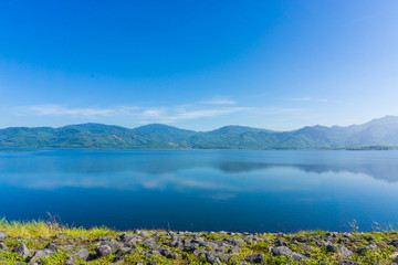 Naklejka na ściany i meble View of reservoir blue sky and green grass