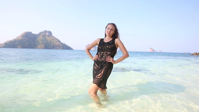 brunette girl in transparent lace frock poses in sea water