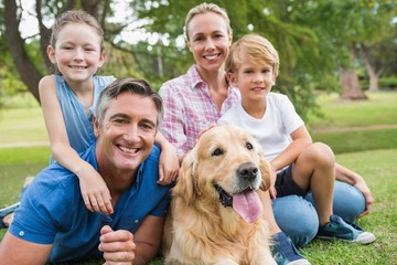 Happy family smiling at the camera with their dog