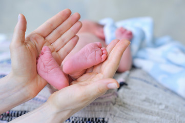Mother holding infant's small feet in her hand