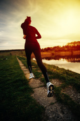 Young woman athlete running in nature at the sunrise 