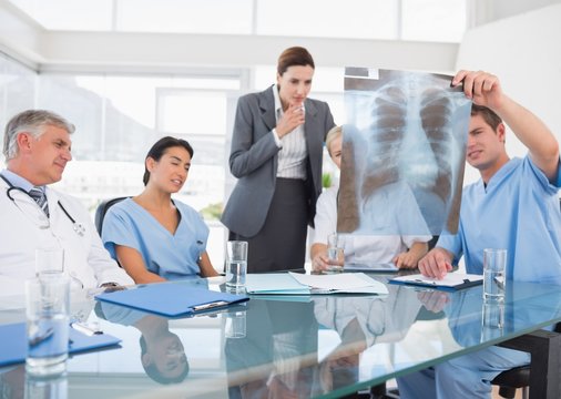 Team of doctors and businesswoman examining xray 