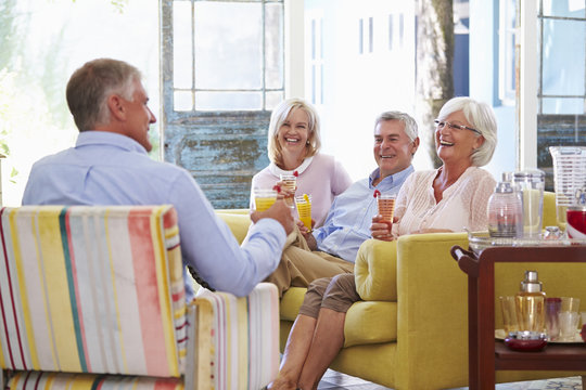 Group Of Friends At Home Relaxing In Lounge With Cold Drinks