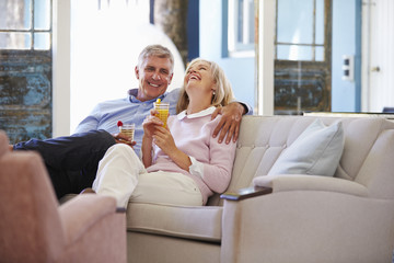 Obraz premium Mature Couple At Home Relaxing In Lounge With Cold Drinks